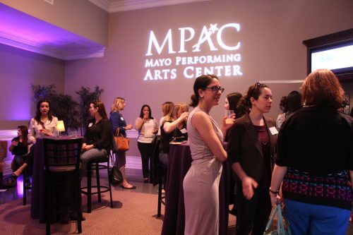 people in business casual gathering around tables, mpac logo in background