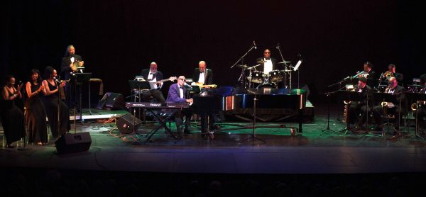 kenny brawner as ray charles on stage with band and background singers